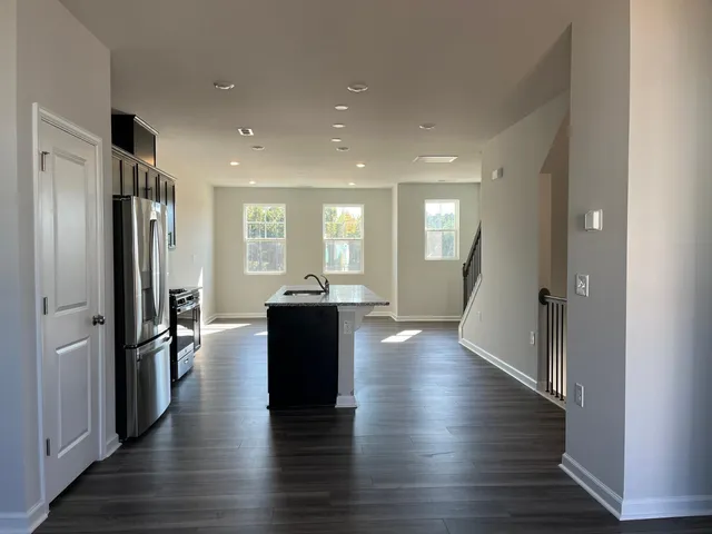 a view of a hallway with wooden floor kitchen view and a refrigerator