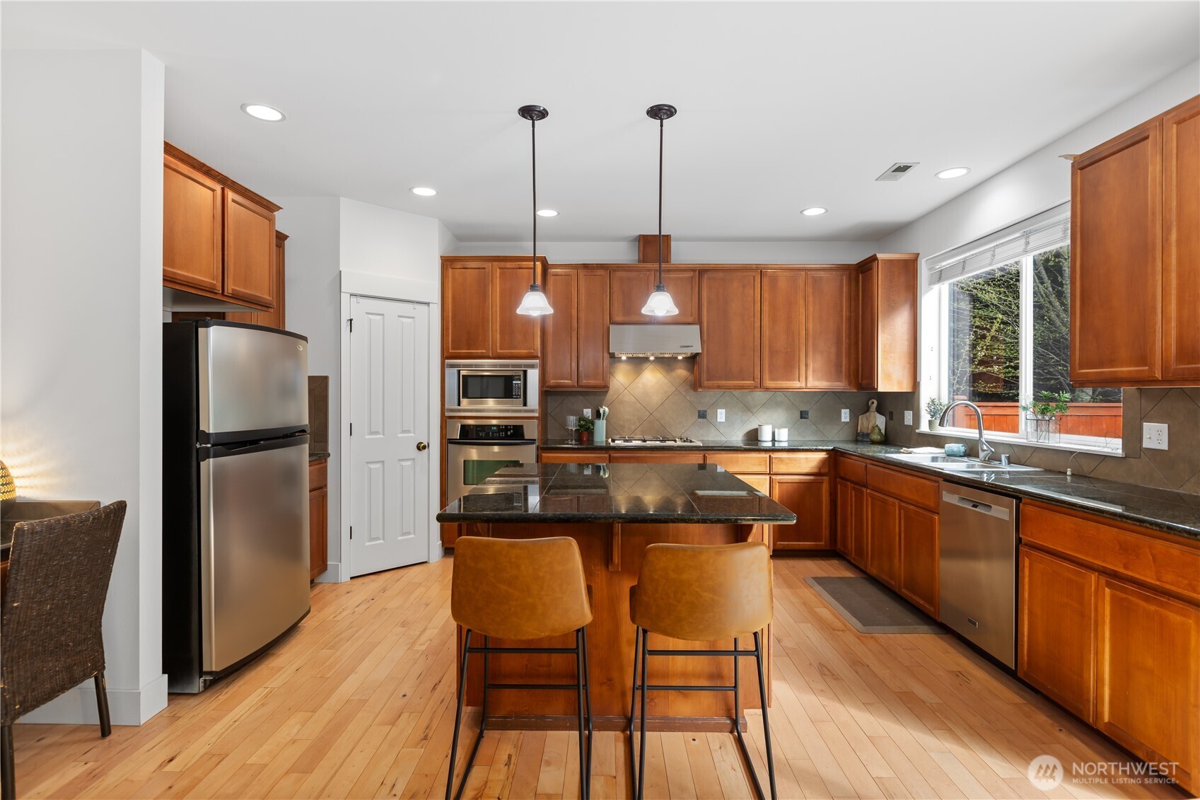22829 36th Avenue Southeast Bothell, WA 98021 - Photo 13 of 39 a kitchen with stainless steel appliances granite countertop a refrigerator a sink dishwasher a stove and a dining table with wooden floor