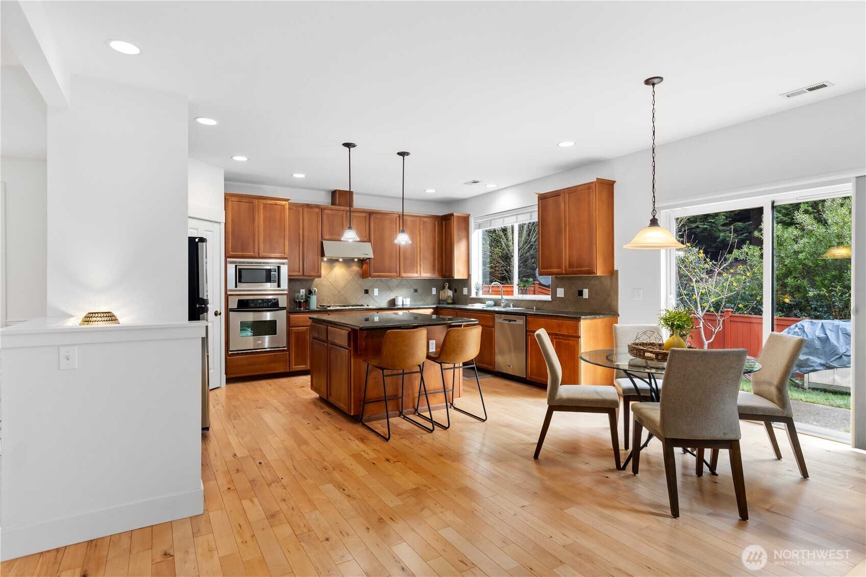 22829 36th Avenue Southeast Bothell, WA 98021 - Photo 10 of 39 a kitchen with stainless steel appliances kitchen island granite countertop wooden floor cabinets dining table and chairs