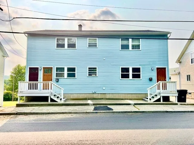 a view of a house with a barbeque and wooden stairs