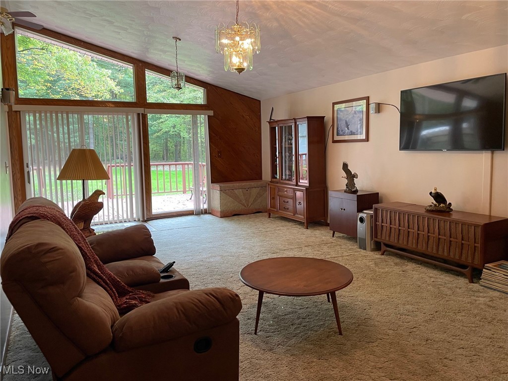 1503 South Leavitt Road Southwest Warren, OH 44481 - Photo 7 of 32 Carpeted living room featuring ceiling fan with notable wood walls, vaulted ceiling, and a healthy amount of sunlight