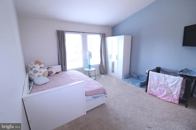 a bedroom with a bed and flat tv screen on the dresser