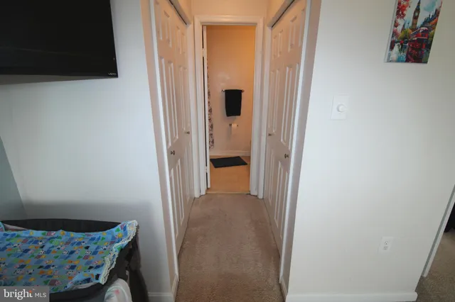 a view of a hallway to room with wooden floor and cabinet