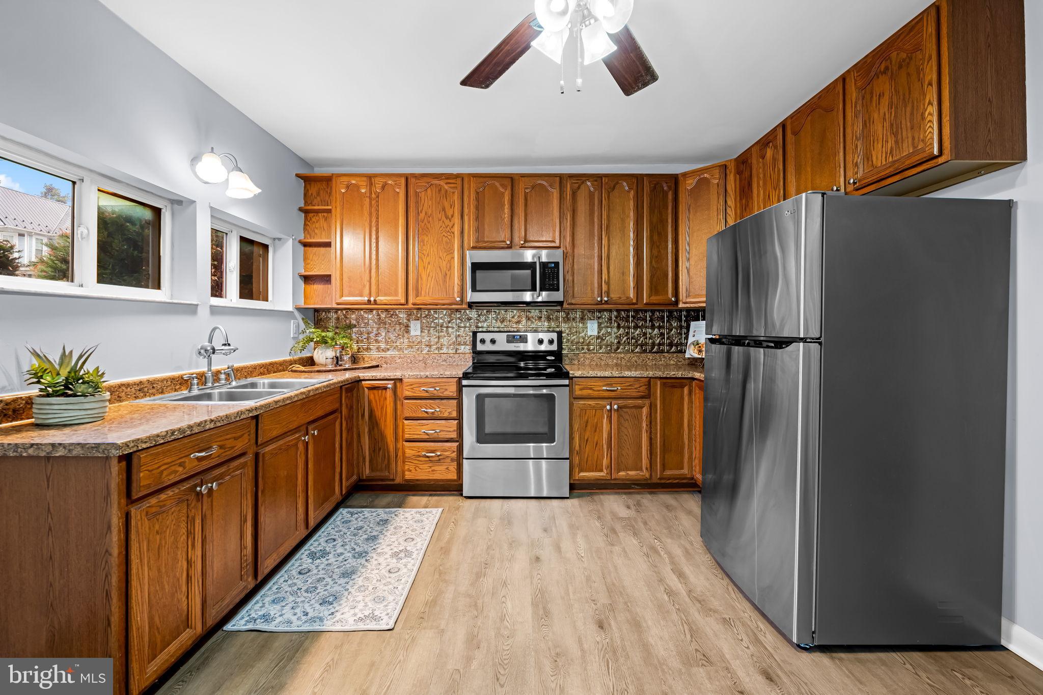 735 Main Street Delta, PA 17314 - Photo 13 of 35 a kitchen with granite countertop wooden floors stainless steel appliances and a window