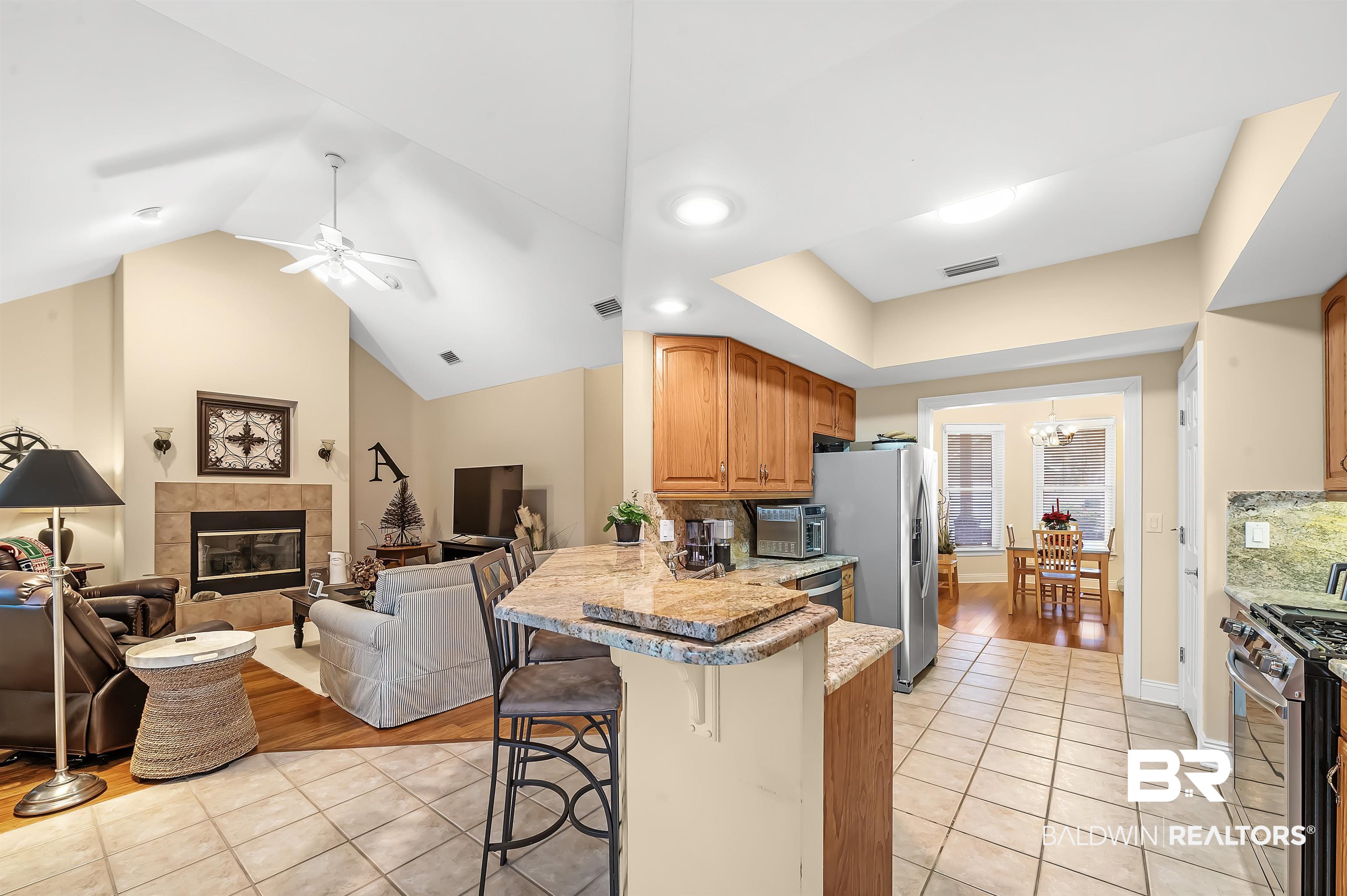 22726 Inverness Way Foley, AL 36535 - Photo 25 of 51 Kitchen featuring kitchen peninsula, backsplash, stainless steel appliances, light tile patterned floors, and a breakfast bar area