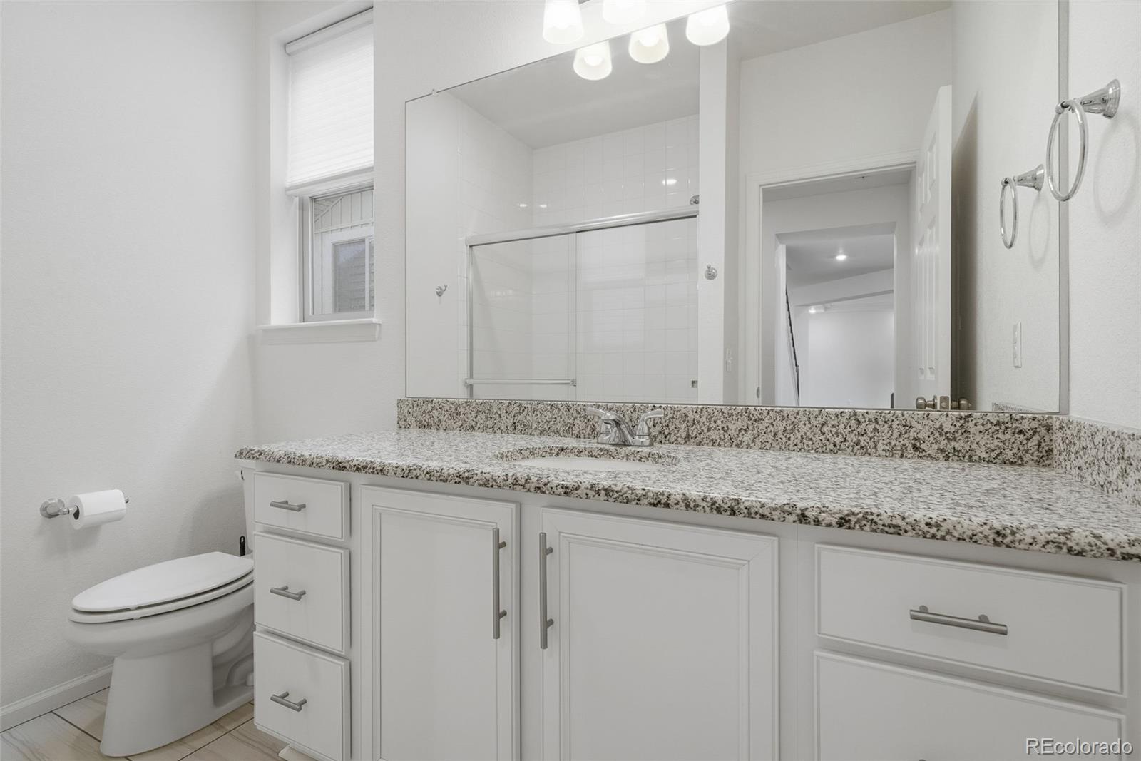5017 Liverpool Street Denver, CO 80249 - Photo 16 of 42 a bathroom with a granite countertop toilet sink and mirror