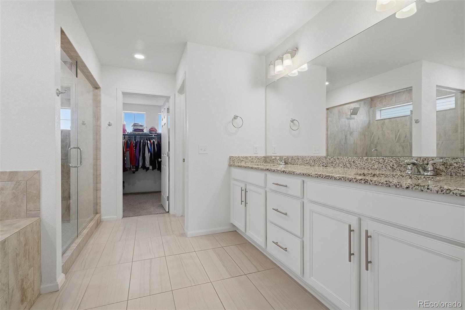 5017 Liverpool Street Denver, CO 80249 - Photo 18 of 42 a spacious bathroom with a granite countertop sink mirror and shower