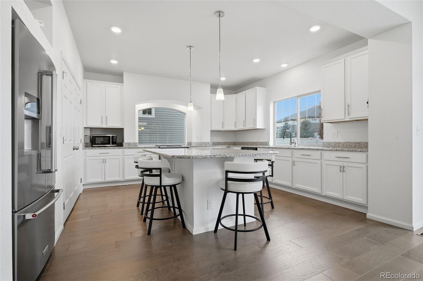 5017 Liverpool Street Denver, CO 80249 - Photo 10 of 42 a kitchen with stainless steel appliances kitchen island granite countertop a table chairs microwave and sink