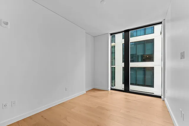 an empty room with wooden floor and bathroom view