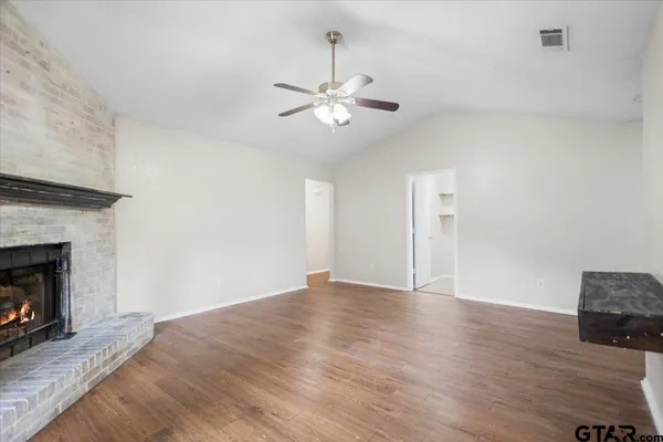 an empty room with wooden floor chandelier fan and windows