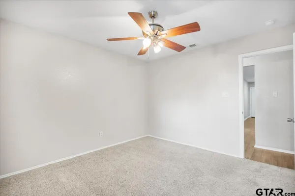 an empty room with windows and fan