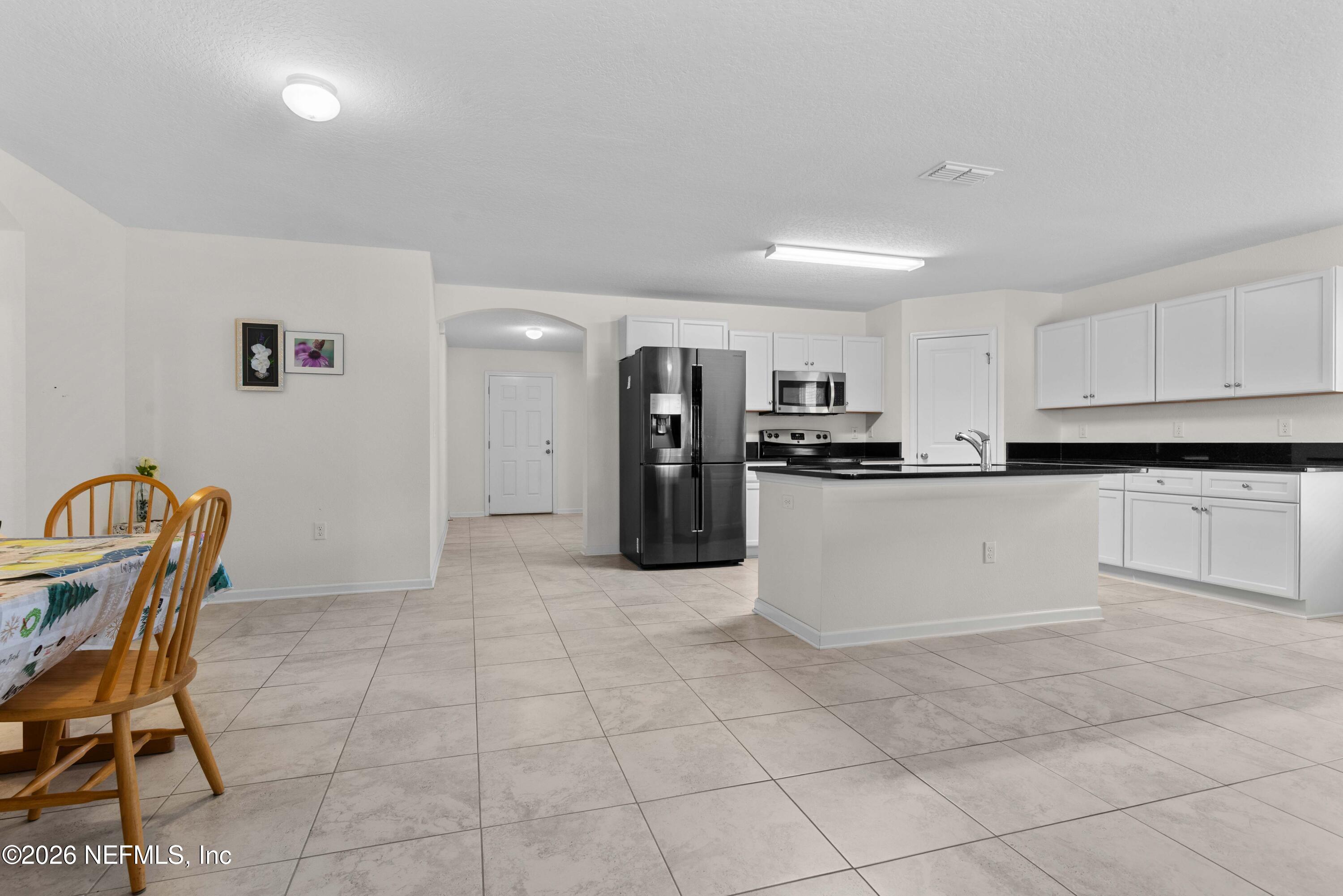 9862 Soldier Court Jacksonville, FL 32221 - Photo 6 of 30 a kitchen with stainless steel appliances kitchen island granite countertop a refrigerator and cabinets