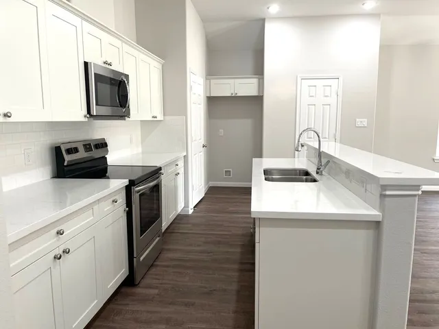 a kitchen with a sink a stove top oven and white kitchen