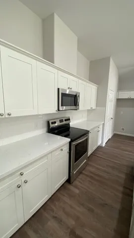 a kitchen with granite countertop white cabinets and white appliances