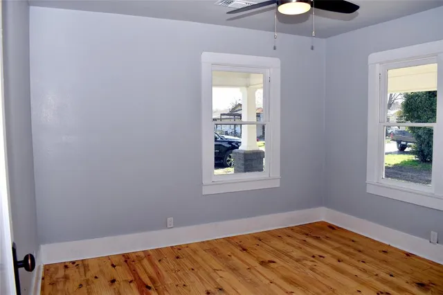 a view of an empty room with window and wooden floor