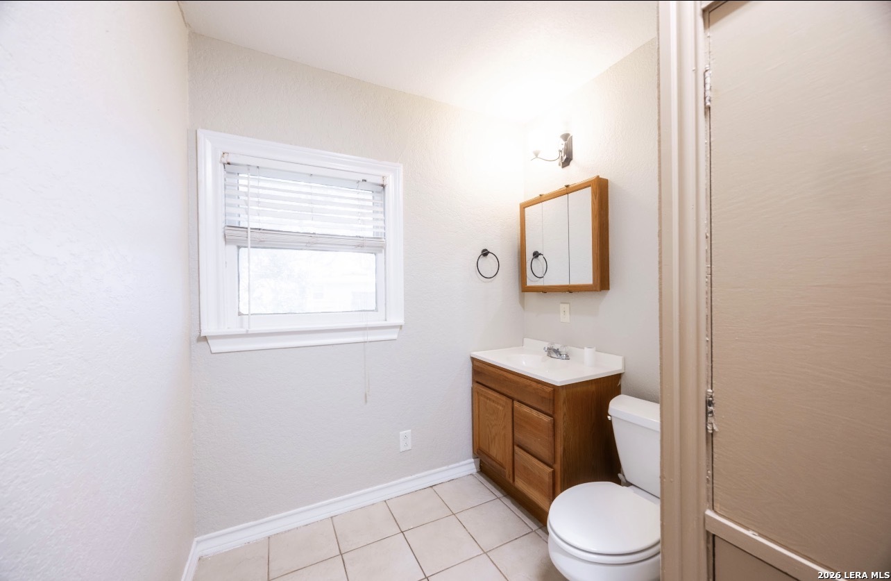 149 South Carroll Street Poth, TX 78147 - Photo 21 of 28 a bathroom with a toilet a sink a mirror and a window