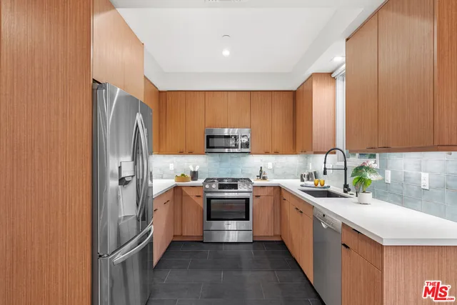 a kitchen with stainless steel appliances granite countertop a stove top oven a sink and dishwasher a refrigerator with wooden cabinets