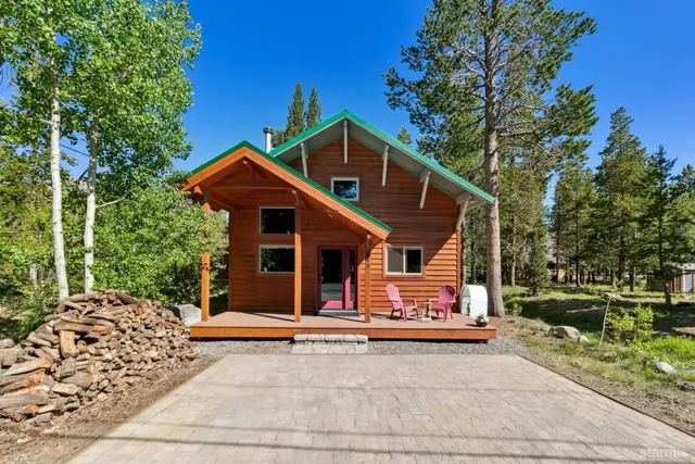a view of a house with a yard plants and large tree