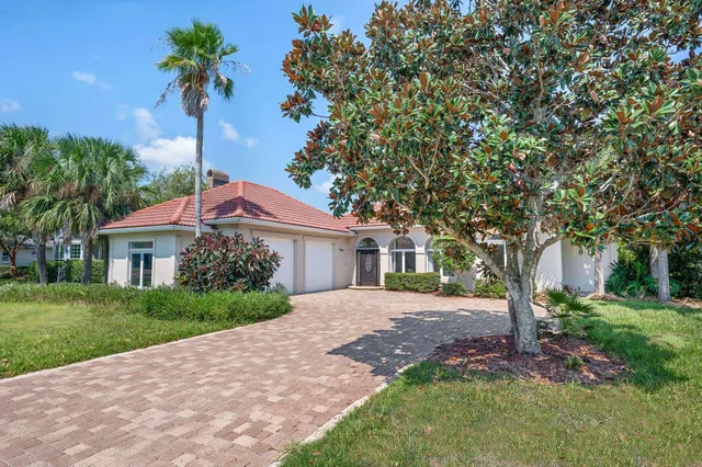 a front view of a house with a garden and trees