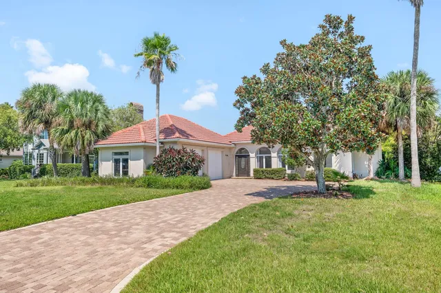 a front view of a house with a yard and trees