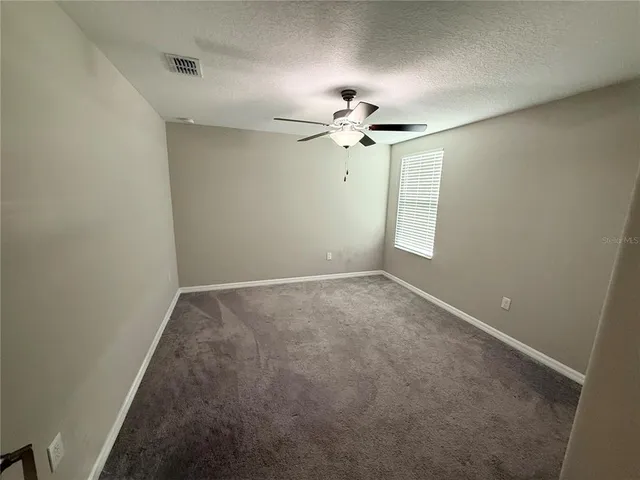 an empty room with a chandelier fan and windows