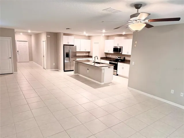a large white kitchen with a stove a sink dishwasher and a refrigerator with wooden floor