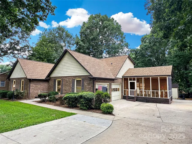 a view of a house with a yard plants and large tree