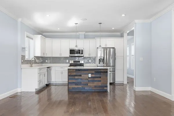 a kitchen with kitchen island granite countertop white cabinets and stainless steel appliances