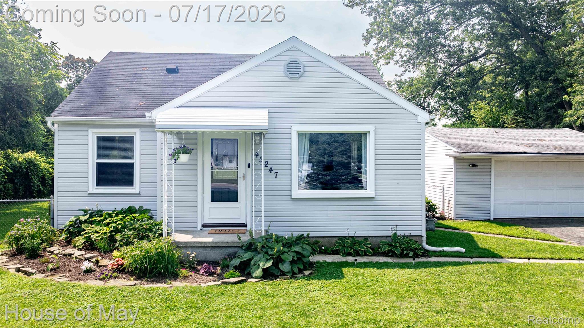 Light gray siding exterior with white trim windows and a covered front entry