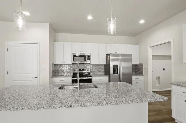 a kitchen with kitchen island granite countertop stainless steel appliances a sink stove and refrigerator