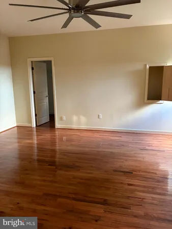 an empty room with wooden floor chandelier fan and windows