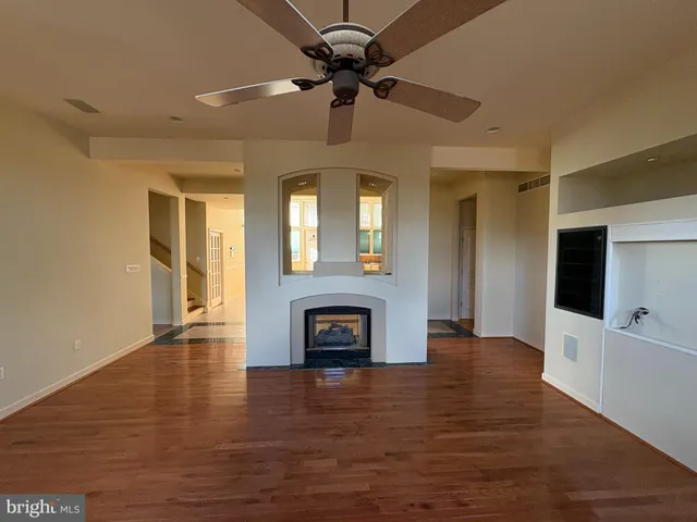 a view of an empty room with wooden floor and windows