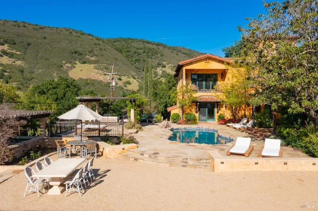 a view of a patio with swimming pool and table and chairs under an umbrella