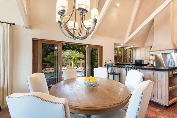 a dining room with furniture a kitchen view and a chandelier