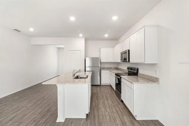a kitchen with cabinets wooden floor and stainless steel appliances