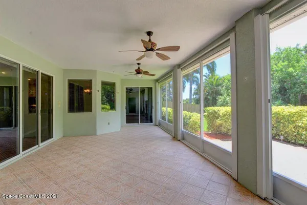 a view of an empty room with windows and ceiling fan