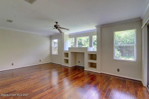 an empty room with wooden floor fireplace and windows