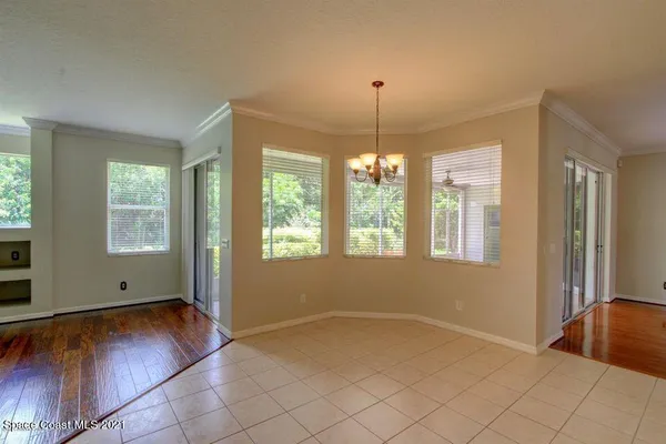a view of an empty room with window and chandelier fan