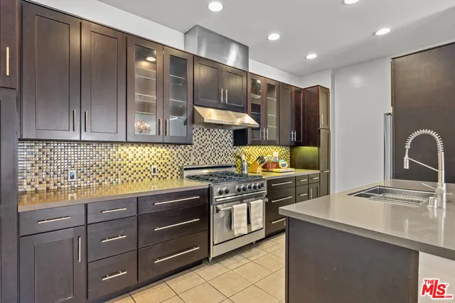 a kitchen with stainless steel appliances granite countertop a refrigerator a stove and a sink with wooden cabinets