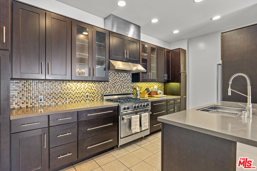 1260 South Beverly Glen Boulevard, Unit 305 Los Angeles, CA 90024 - Photo 13 of 28 a kitchen with stainless steel appliances granite countertop a refrigerator a stove and a sink with wooden cabinets