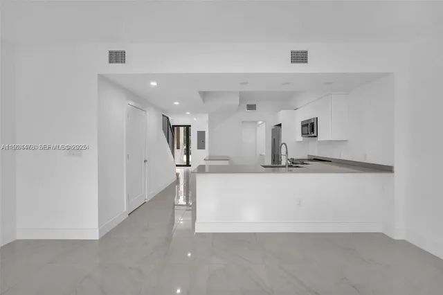 a large white kitchen with kitchen island a sink a stove and white cabinets