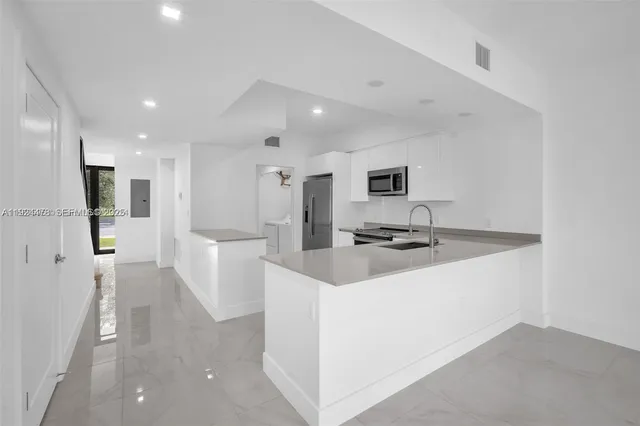 a kitchen with a sink stainless steel appliances and white cabinets