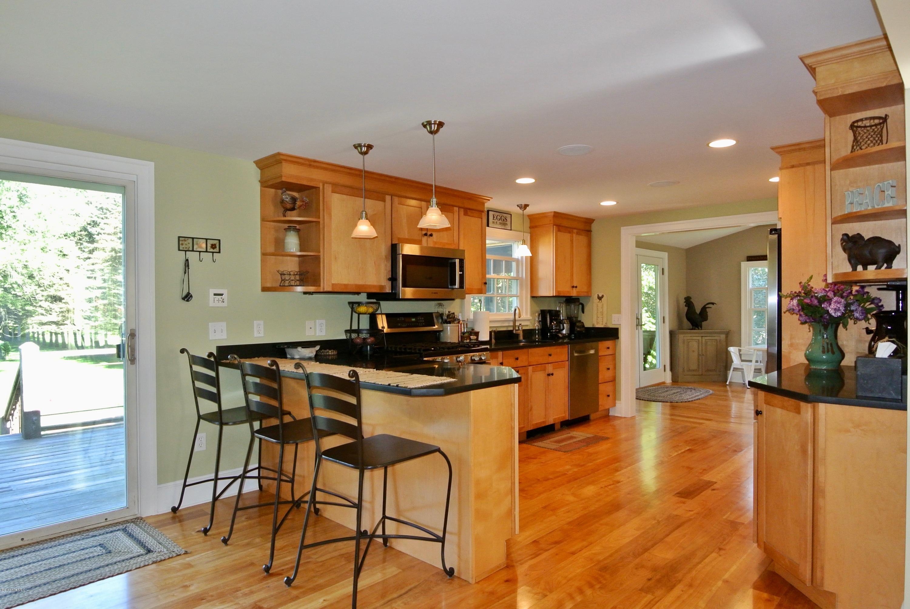 3136 State Road Richmond, MA 01254 - Photo 17 of 29 a kitchen with stainless steel appliances kitchen island granite countertop a stove a refrigerator a sink a dining table and chairs with wooden floor