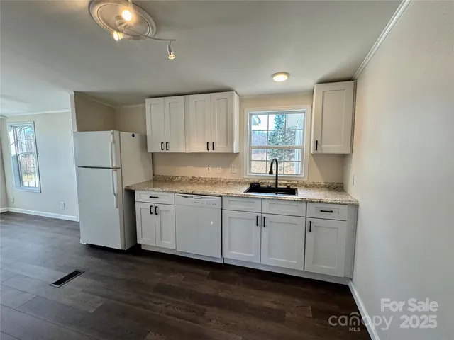 a kitchen with granite countertop white cabinets and refrigerator