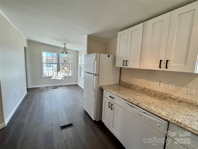 a kitchen with a refrigerator a sink and wooden floor