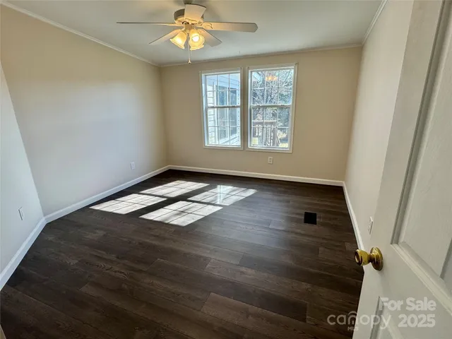 an empty room with wooden floor cabinet and windows