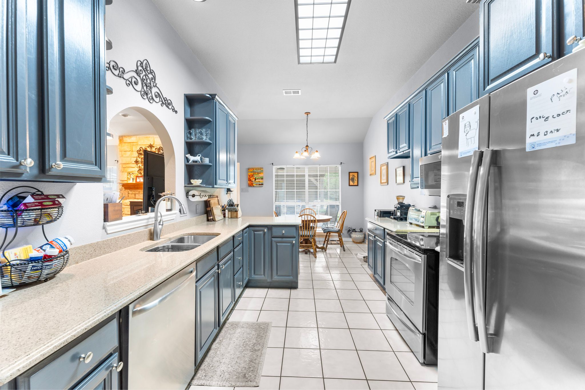 221 Breakaway Road Cedar Park, TX 78613 - Photo 25 of 39 Kitchen featuring stainless steel appliances, a sink, light tile patterned floors, open shelves, and arched walkways