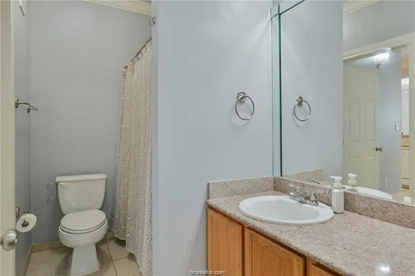 a bathroom with a granite countertop sink a toilet and a mirror