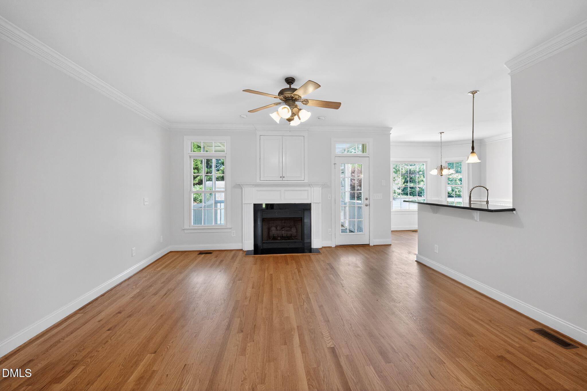8725 Oregon Inlet Court Raleigh, NC 27603 - Photo 6 of 31 an empty room with wooden floor fireplace and a kitchen view