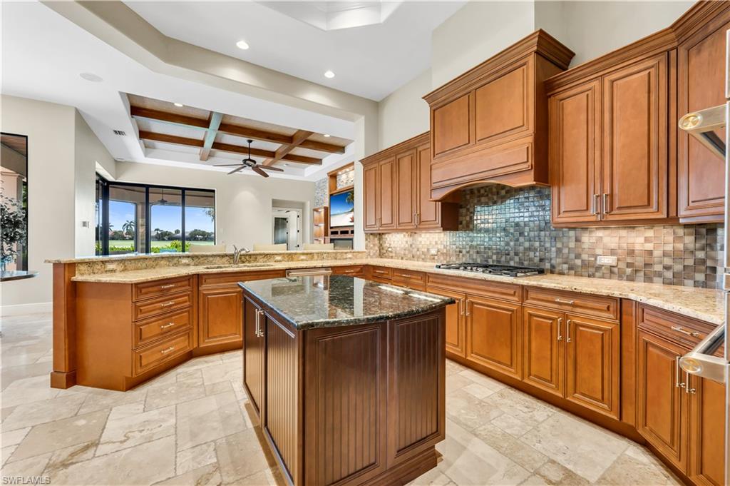11875 Hedgestone Court Naples, FL 34120 - Photo 10 of 29 Kitchen featuring wood cabinetry, a center island, stone countertops, a tile backsplash, and recessed lighting